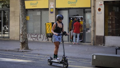 Una 'rider' de Glovo frente a un supermercado express de la compañía en Barcelona, el 25 de junio de 2025.