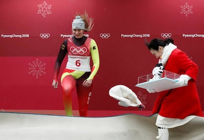 Uma mulher perde seu gorro para o vento enquanto a esportista alemã Natalie Geisenberger sobe ao pódio para receber sua medalha de ouro pela competição de luge individual.