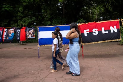 Una familia camina frente a las banderas de Nicaragua y del Frente Sandinista de Liberación Nacional durante la celebración del aniversario 46 de la revolución popular Sandinista en Managua.