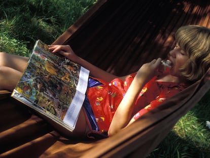 Una niña leyendo un libro de animales en una hamaca.