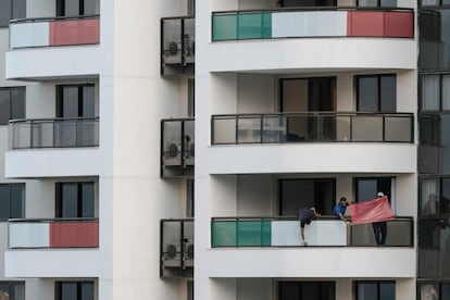 Operarios colocan los colores de la bandera italiana en los balcones de los apartamentos.