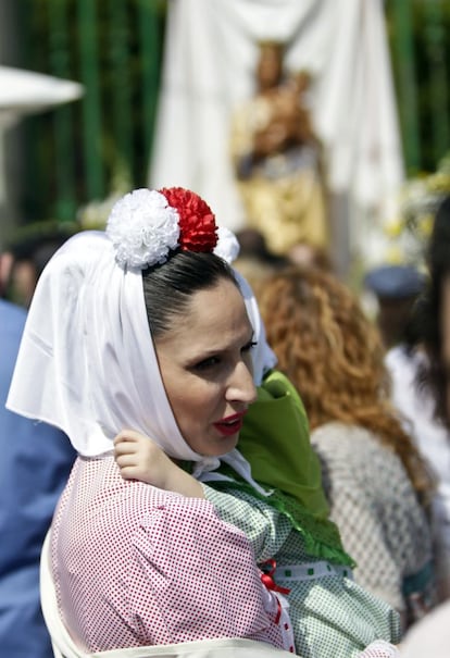 Una mujer sujeta a su hija cerca de la imagen de San Isidro Labrador.