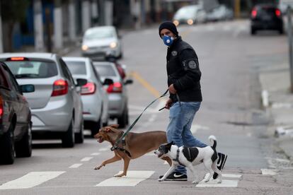 Un hombre con tapabocas pase a sus perros en una calle de Sao Paulo (Brasil).