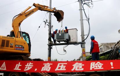 Dos operarios trabajan para arreglar un transformador, en Nanyang, provincia de Henan.