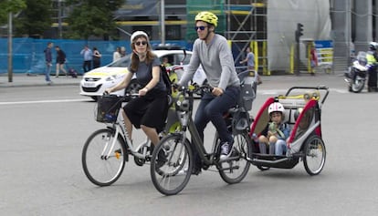 Dos ciclistas pedalean llevando a varios niños durante la manifestación.