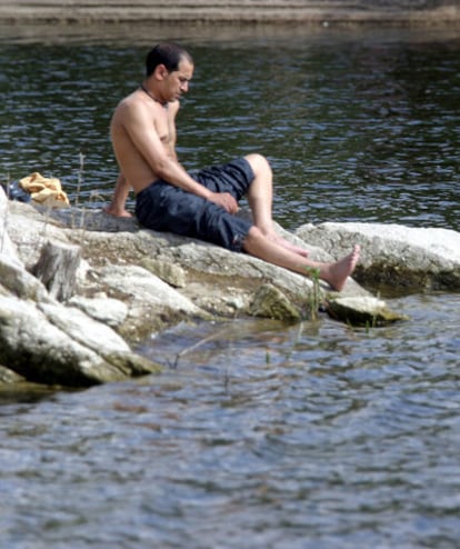 Un visitante toma el sol junto al embalse de Valmayor, un sitio donde no se permite bañarse.