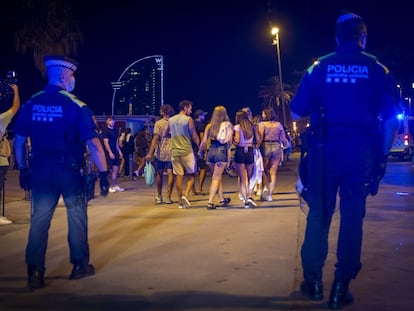 Una pareja de policías desaloja a un grupo de personas que permanecía en la calle tras el toque de queda en Barcelona.