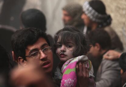 Un joven lleva una niña herida que sobrevivió a lo que los activistas dicen que fue un ataque aéreo de las fuerzas leales al presidente sirio, Bashar al-Assad en el barrio Duma de Damasco.