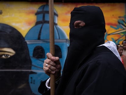 Penitente de la Hermandad de Jesús de Nazareno junto a un mural con su figura en el municipio de San Diego, Cesar, el 6 de abril de 2023.