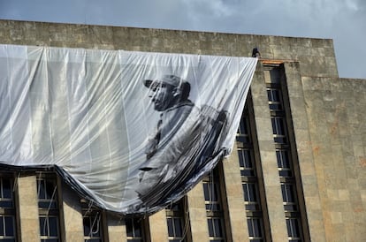 Operário desfralda painel com foto gigante de Fidel Castro quando na guerrilha. 