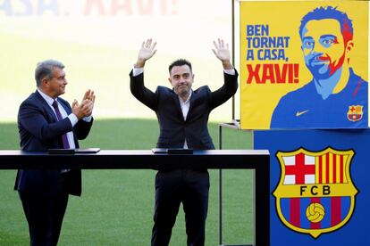 Xavi Hernández (derecha), junto al presidente del club, Joan Laporta, saluda a los aficionados que se han citado en las gradas del Camp Nou durante el acto de presentación del exjugador como nuevo entrenador del FC Barcelona.