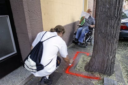 Un activista señala con <i>spray</i> un obstáculo a la movilidad de un vecino en silla de ruedas.