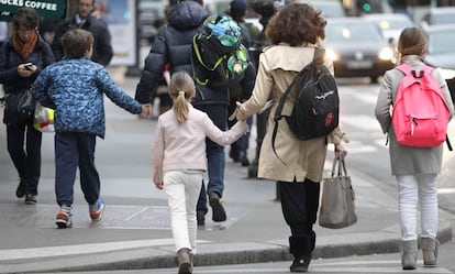 Una madre acompaña a sus hijos al colegio.