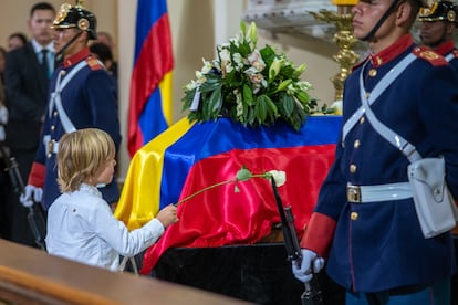 El hijo de Miguel Uribe Turbay, Alejandro, coloca una flor en el feretro del senador fallecido, en la Catedral Primada, este miercoles.