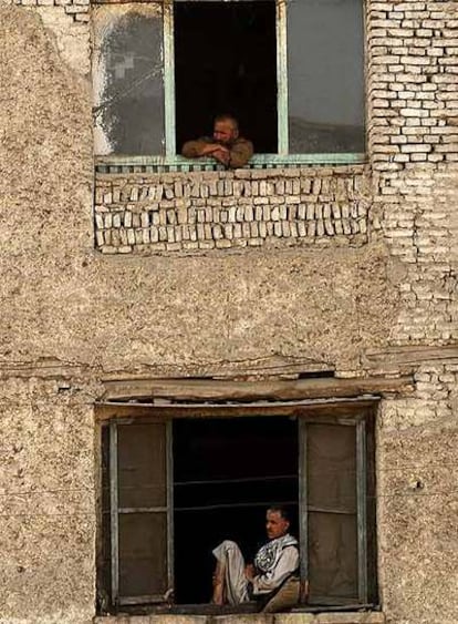 Dos afganos observan por la ventana en un edificio de Kabul.