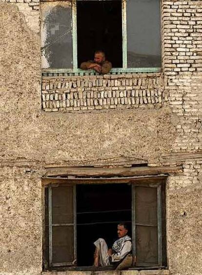 Dos afganos observan por la ventana en un edificio de Kabul.