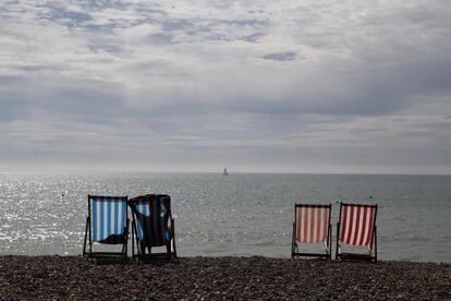 Una mujer toma el sol en una tumbona junto al mar en un día soleado en la playa de Brighton (Reino Unido).