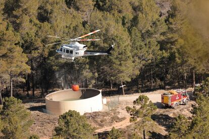 Dotaciones de bomberos y un helicóptero trabajan en la extinción del incendio en la zona de los Peiros, en la provincia de Teruel, este sábado.