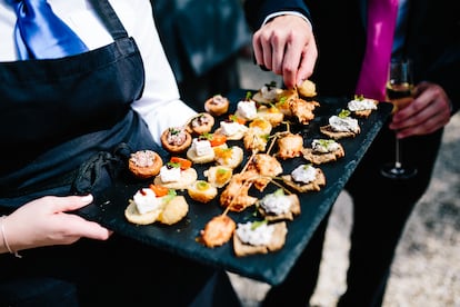 Un invitado elige uno de los canapés de un plato variado.