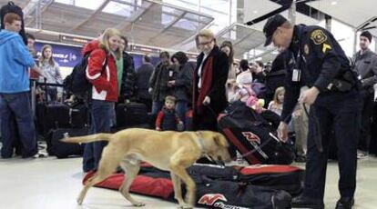Un policía registra, ayudado por un perro adiestrado, el equipaje de los viajeros en el aeropuerto de Detroit.
