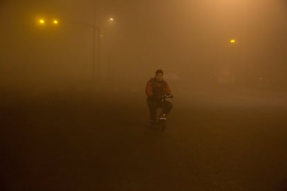 Un hombre atraviesa la niebla en bicicleta en Pekín (China).