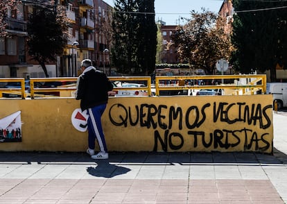 Un hombre pasa  junto a una pintada contra los turistas en el distrito de Puente de Vallecas, el mes de marzo.
