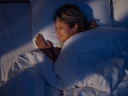 Una joven sonríe mientras duerme por la noche.