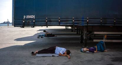 Unos hombres descansan bajo unos camiones en el puerto del Pireo, donde casi 1.500 refugiados y migrantes viven en un campamento improvisado.