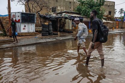 Dos jóvenes atraviesan una calle inundada en Grand Dakar. Las lluvias torrenciales han bloqueado ya en tres ocasiones las principales arterias y vías secundarias de la capital senegalesa a principios del presente mes de agosto. El Gobierno ha activado el plan ORSEC para socorrer a los vecinos más afectados.