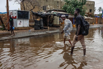 Dos jóvenes atraviesan una calle inundada en Grand Dakar. Las lluvias torrenciales han bloqueado ya en tres ocasiones las principales arterias y vías secundarias de la capital senegalesa a principios del presente mes de agosto. El Gobierno ha activado el plan ORSEC para socorrer a los vecinos más afectados.