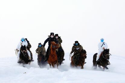 Autoridades fronterizas viajan en caballo para visitar aldeas remotas e informar sobre el coronavirus a sus residentes en Altay, provincia de Xinjiang (China).