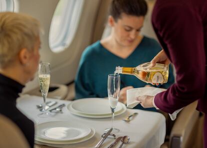 The cabin crew serves travelers Ruinart champagne.