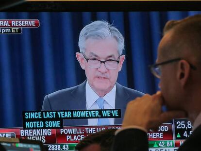 En la pantalla el presidente de la Reserva Federal, Jerome Powell, bajo la mirada de un agente de Bolsa en el parqué de la Bolsa de Nueva York