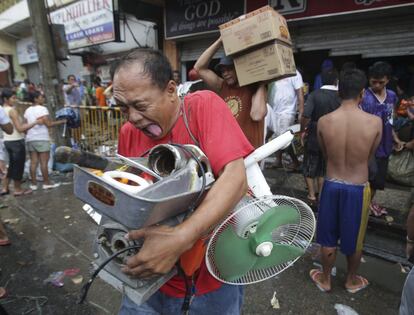 Un residente Filipino reacciona después de recibir los suministros de un supermercado que fue asaltado en Tacloba , provincia de Leyte, Filipinas