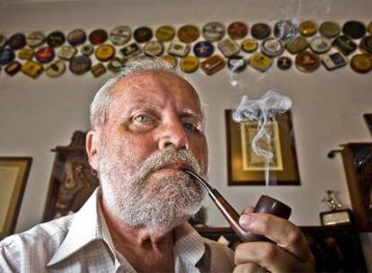 Juan Bonet en su casa de Palma fumando debajo de algunas de las cajas de mixturas de tabaco que colecciona.