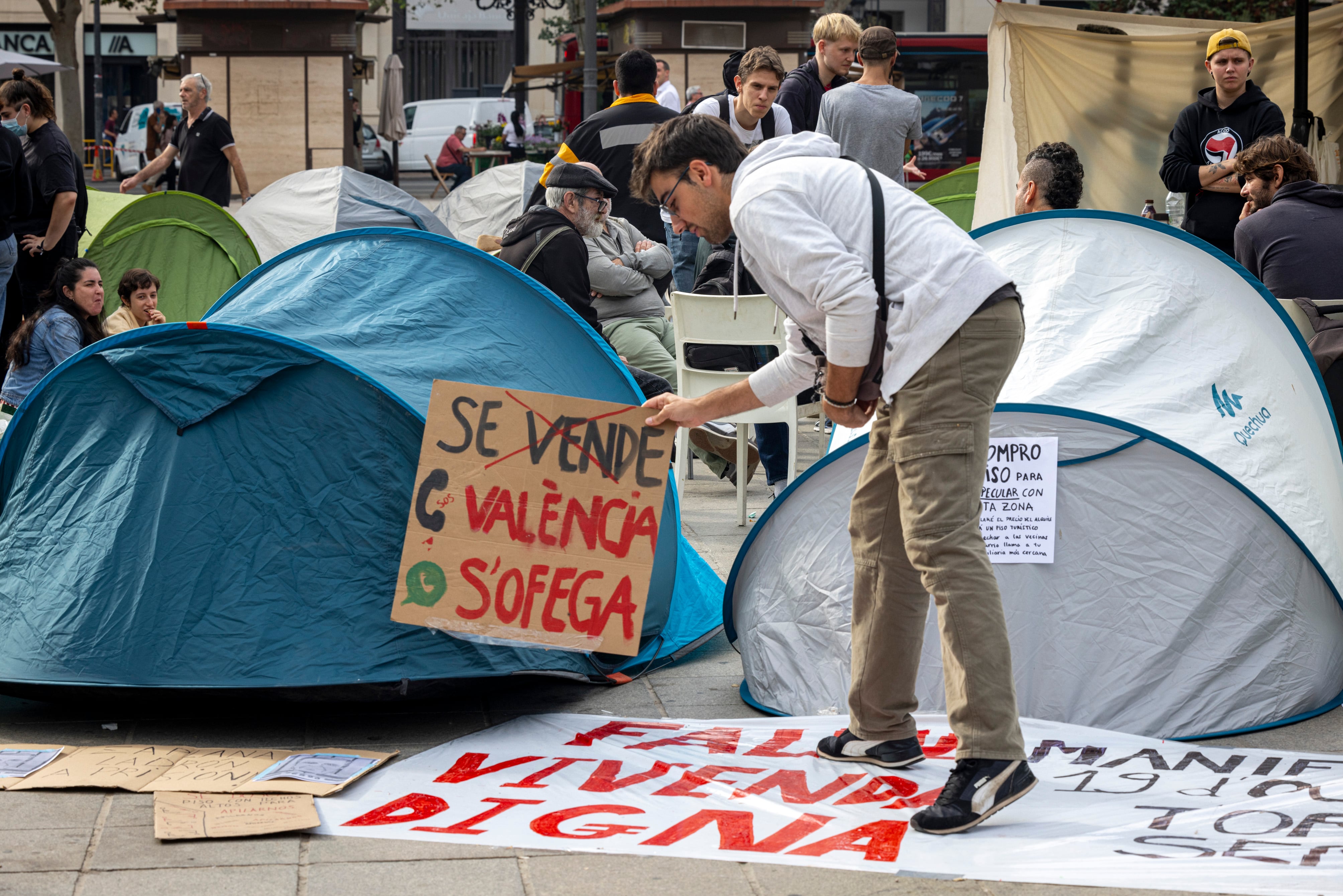 Un joven acampado coloca un cartel con el lema 