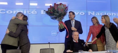 Alicia Sánchez-Camacho se abraza a Javier Arenas mientras Mariano Rajoy sostiene un ramo de flores, ayer en Madrid.