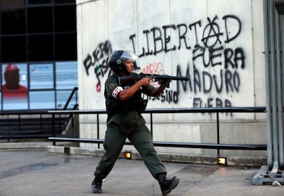 Un oficial de la Guardia Nacional Bolivariana, carga contra los manifestantes antigubernamentales, ante un muro con una pintada en contra de Maduro.