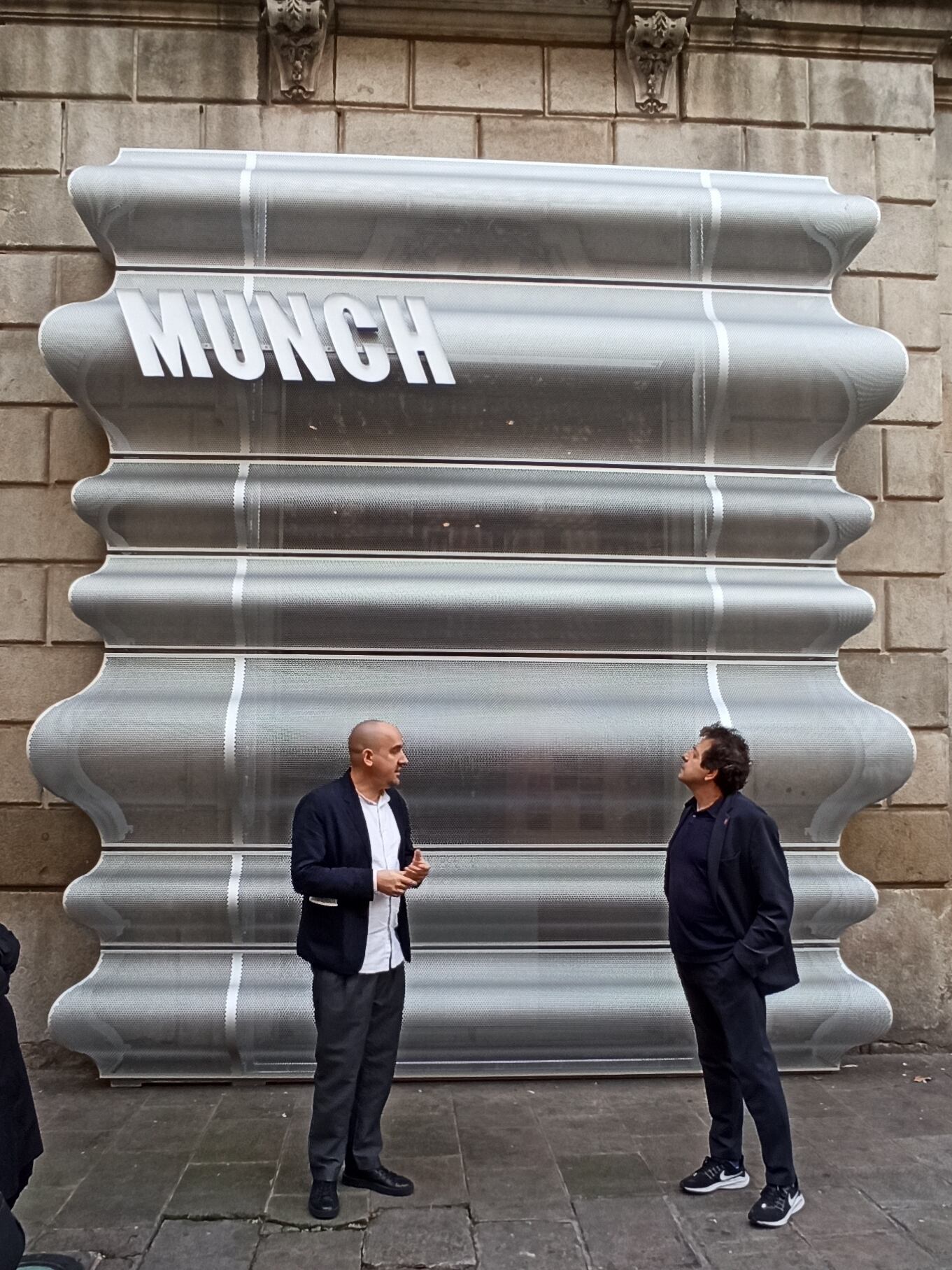 El arquitecto Juan Herreros (derecha) y su socio Jens Richter en la puerta de La Virreina, junto al fragmento de fachada del museo Munch de Oslo.