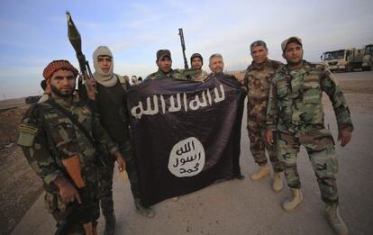 Combatientes iraqu&iacute;es chi&iacute;es posan con una bandera arrebatada al EI. 