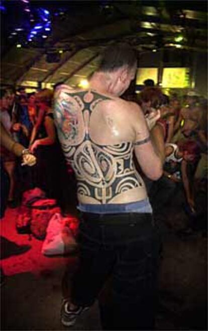 Un joven tatuado, bailando en una carpa del festival.