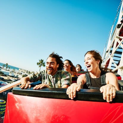 Laughing and screaming couple riding roller coaster at amusement park