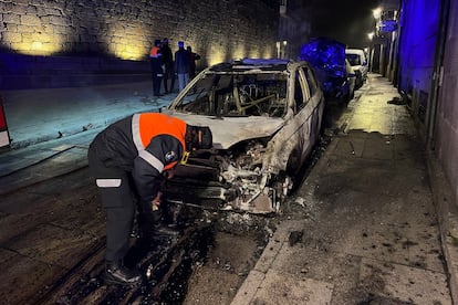 Un agente observa uno de los vehículos quemados en Tui (Pontevedra).