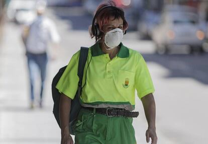 Una trabajadora de la limpieza camina protegida con mascarillas.
