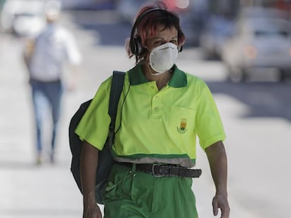 Una trabajadora de la limpieza camina protegida con mascarillas.