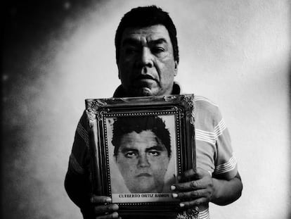 Oscar Ortiz Serafin segura a foto de seu filho Cutberto Ortiz Ramos em uma sala de aula transformada em dormitório para as famílias dos alunos desaparecidos da Escola Rural de Ayotzinapa.