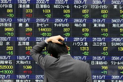 Un hombre mira los valores de la bolsa de Tokio este lunes, primer día con los mercados abiertos tras el terremoto.