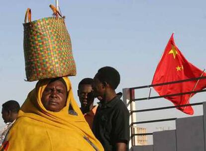 Habitantes de Jartum, con una bandera china al fondo, días antes de la visita del presidente Hu Jintao en febrero.