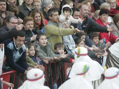 Los sevillanos piden a los Reyes Magos caramelos al paso de la cabalgata.