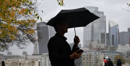 Imagen de un viandante junto al río Támesis, con la City de Londres al fondo. 